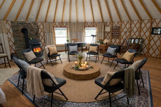 A circle of chairs inside a warmly lit yurt at The Gentle Wild, prepared for a small listening and storytelling gathering.