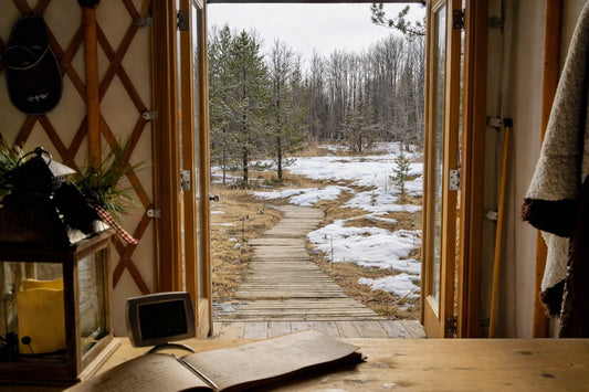 Looking out the yurt door, the forest, the grasses still partially covered in snow. Looking forward.