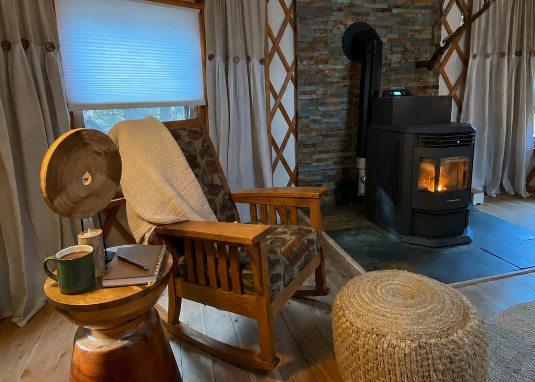 Cozy living room with wooden furniture, stone fireplace, and large window.